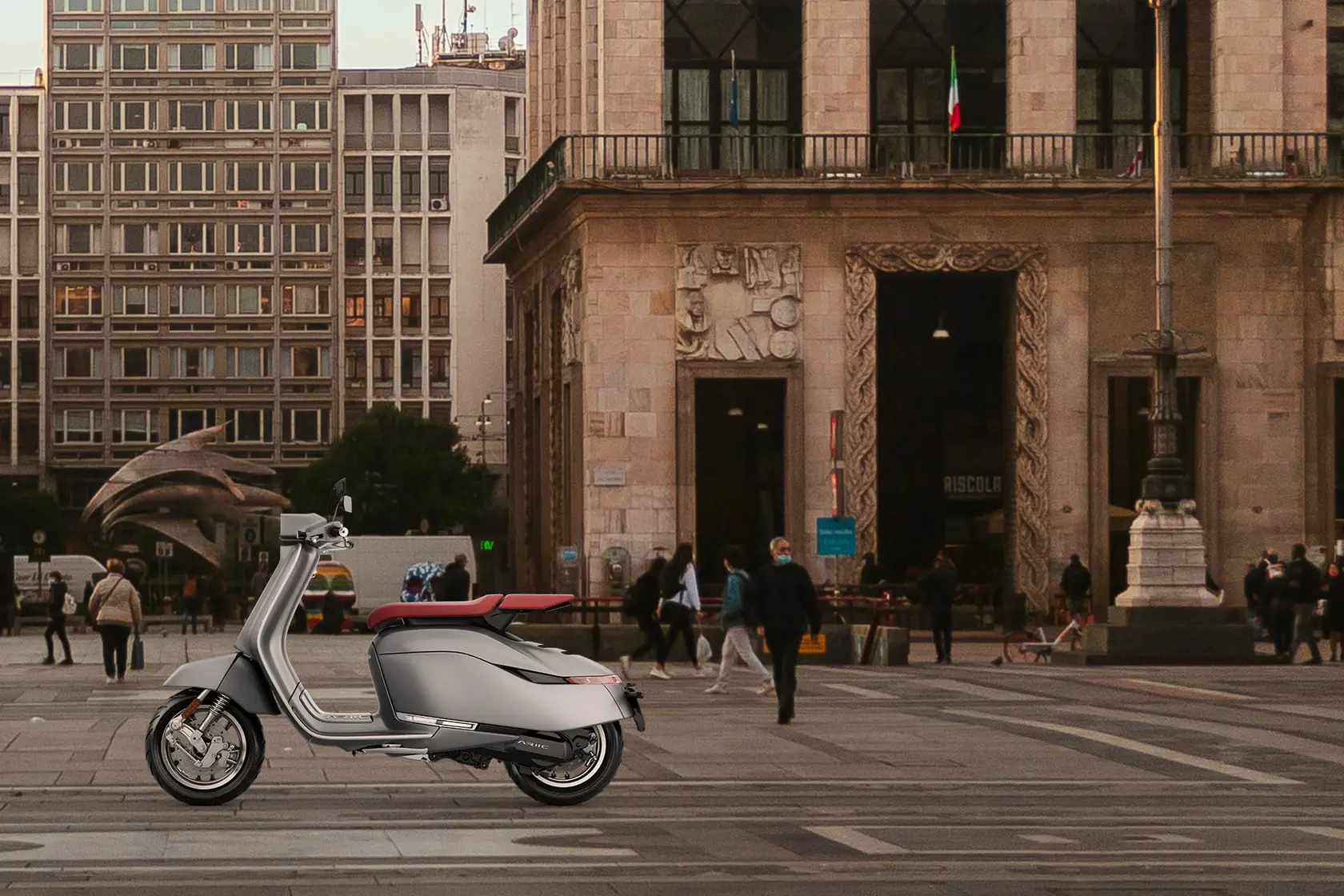 Brio II at the edge of a busy city square, in front of an old stone building
